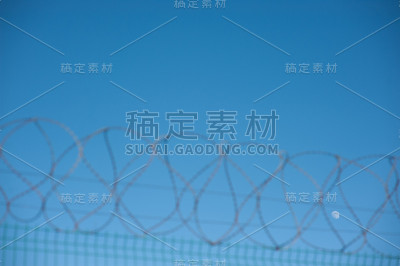 非法移民危机概念上的带刺铁丝网，背景上的蓝天和月亮与空间的复制