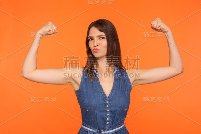 女权主义和女性力量。自信独立的黑发女人在牛仔裙显示二头肌