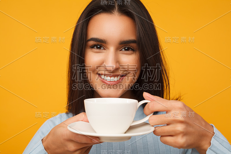 西班牙裔年轻女子微笑着，手里拿着一杯咖啡