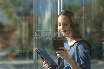 学生在公交车站检查智能手机