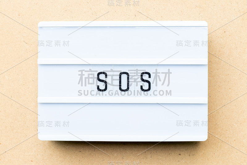 白色灯箱字SOS(拯救我们的灵魂/船或兄弟姐妹的缩写)在木材背景上