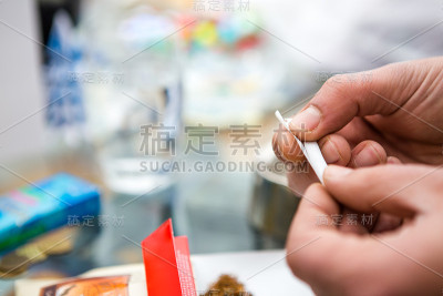 一个男人的手的特写，他只是手工制作了一根香烟和一张纸。