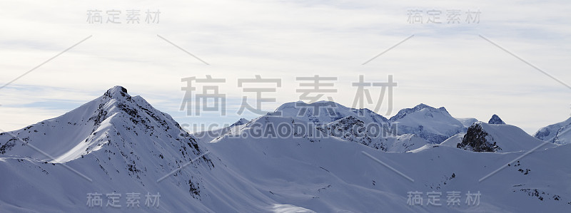 冬季的高山，雪坡和早晨阳光明媚的多云天空