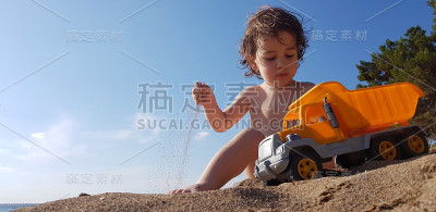 一个小男孩在海滩上玩玩具卡车