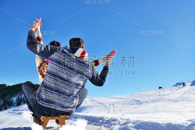 一对年轻夫妇在阳光明媚的冬日里玩雪橇