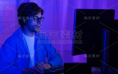 眼镜程序员在电脑上编程，在家里，低灯光