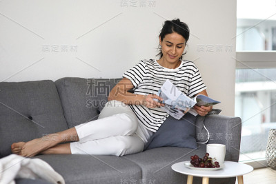 穿着休闲装的漂亮女人坐在她的沙发上消费