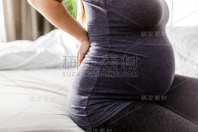 怀孕期间腰痛，孕妇在家坐在床上