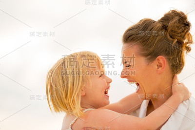 晚上，妈妈和小女孩在海滩上拥抱