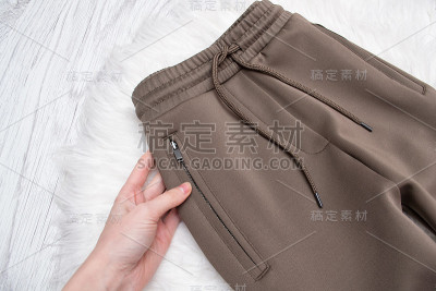 棕色裤子，女性手拉链。时尚的概念