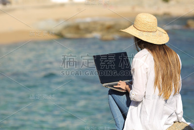 一个女人在沙滩上用笔记本电脑打字