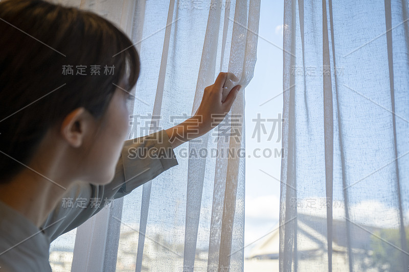 年轻女子在客厅拉开窗帘