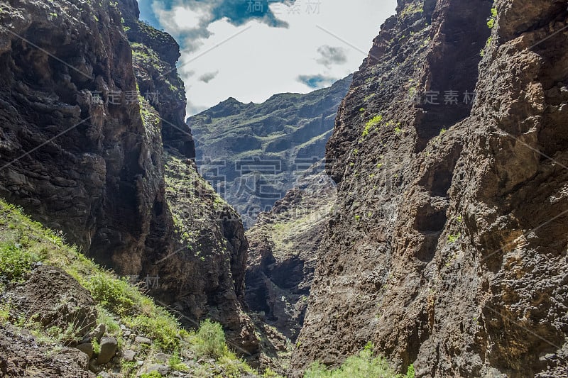 特内里费岛马斯卡峡谷的岩石，显示出凝固的火山熔岩流层和拱形构造。峡谷或峡谷从900米的高度通向海洋