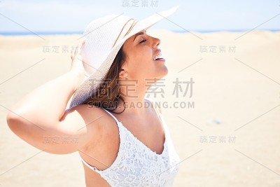 年轻美丽的女人日光浴张开双臂享受夏天在马斯帕洛马斯沙丘海滩
