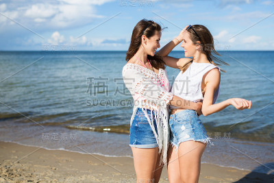 两个快乐的女性朋友站在沙滩上拥抱