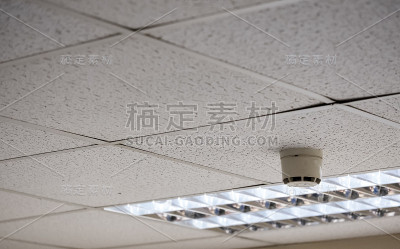 现代办公室内悬挂天花板和烟雾探测器的详细视图。