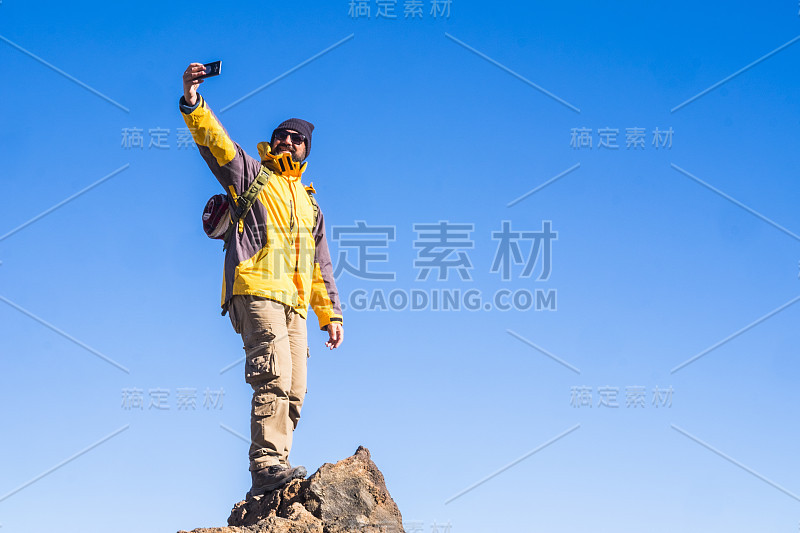 冒险人站在户外以蓝天为背景的山顶上——旅行和徒步旅行的概念或徒步旅行的体育活动——户外的人和科技