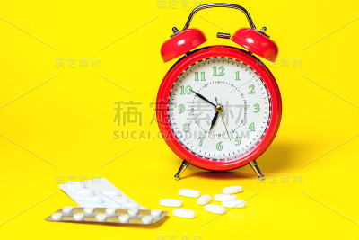 闹钟，彩色背景上的药丸。医疗保健理念
