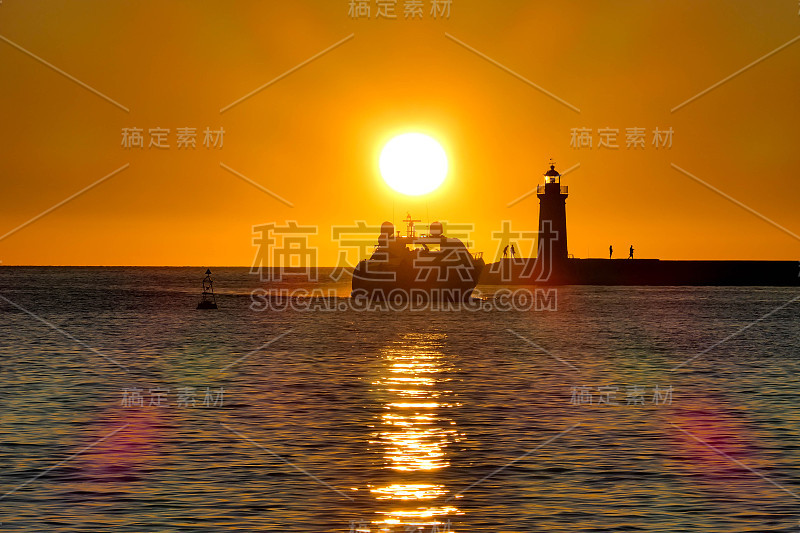 A boat is sailing on the sea at sunset and a light