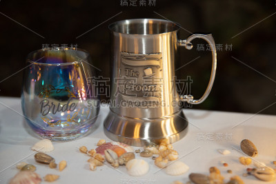 新郎啤酒杯和新娘酒杯放在甲板椅上装饰，沙滩主题餐桌设置在婚宴上