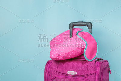 旅行概念-粉红色手提箱前面的蓝色背景