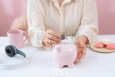 女手把硬币放进存钱罐