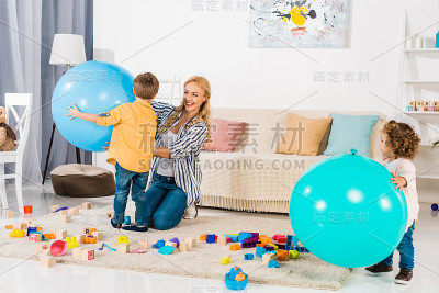 快乐的妈妈和孩子们在家里玩健身球和彩色积木