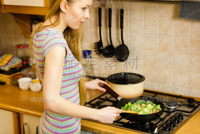女人做饭用平底锅炒速冻蔬菜
