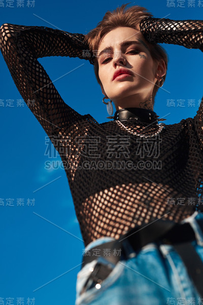 城市的风格。年轻时尚的女人在颈链站在户外摆姿势保持头感性的底部视图