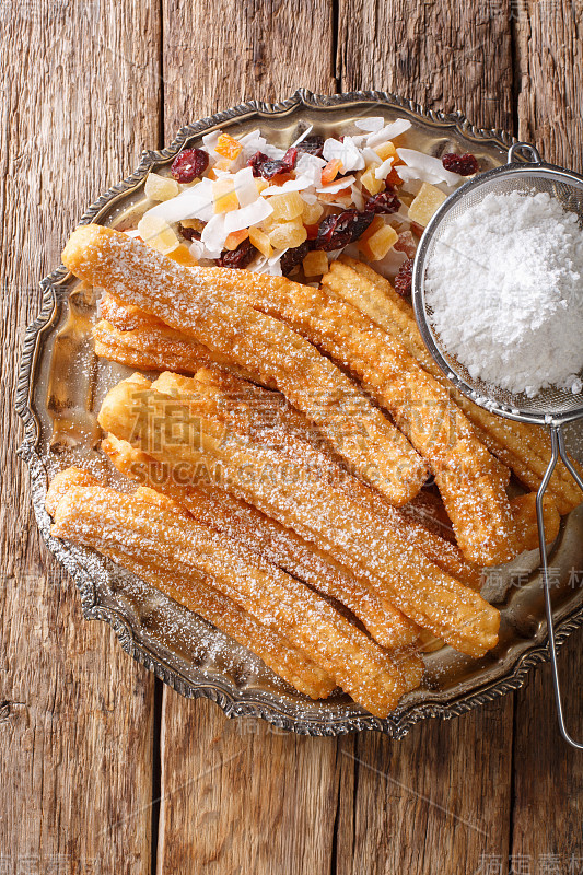 美味的自制油条糖粉和蜜饯水果特写。垂直的俯视图