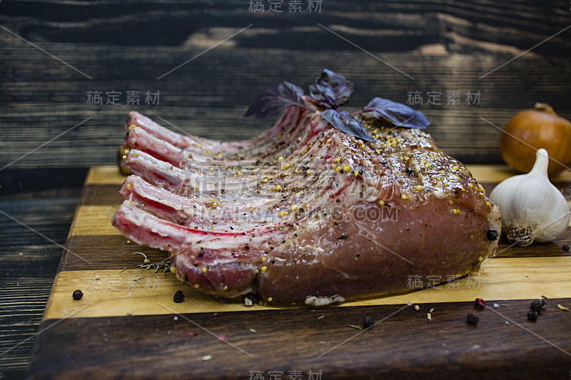 切成薄片的生排骨与香料和香草迷迭香，百里香，罗勒，盐和胡椒在深色的黑色木制背景下的乡村风格