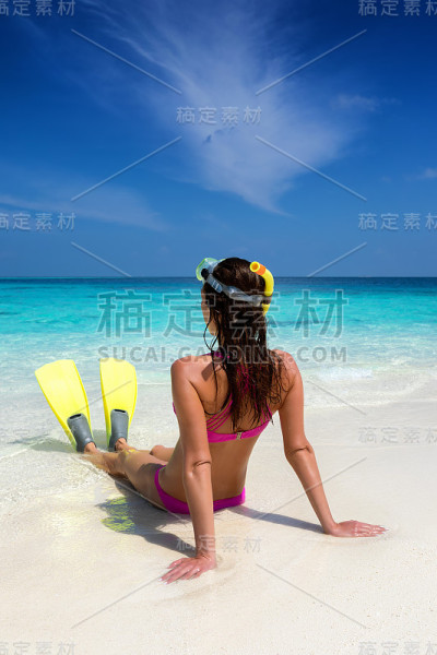一个穿着潜水装备的女人坐在热带海滩上