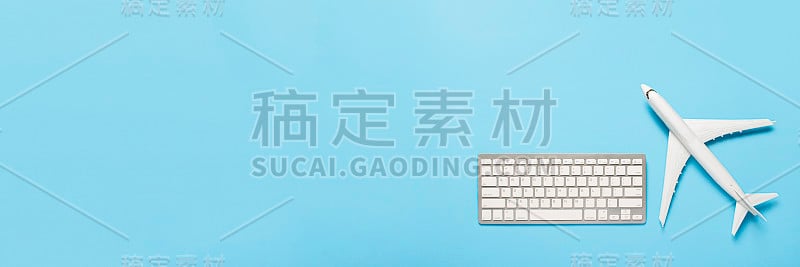 蓝色背景上的键盘和飞机。旅游规划的概念，网上购买机票，销售机票。横幅。平躺，俯视图