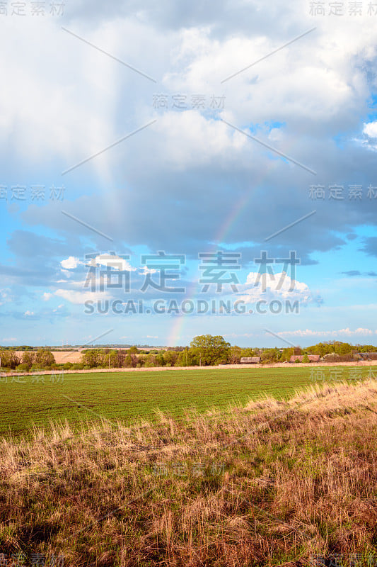 一场春雨过后，彩虹与白云映在蓝天上。由光在水滴中反射、折射和散射而引起的气象现象。