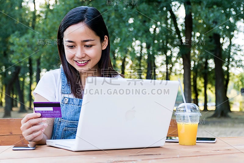 一个印尼女孩用笔记本电脑和信用卡在网上购物