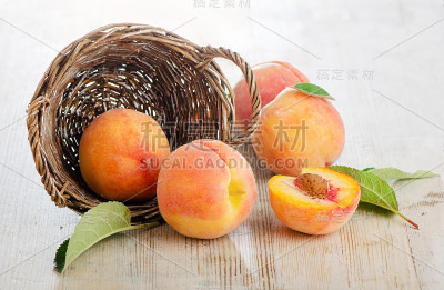 木桌上的篮子里放着新鲜的桃子