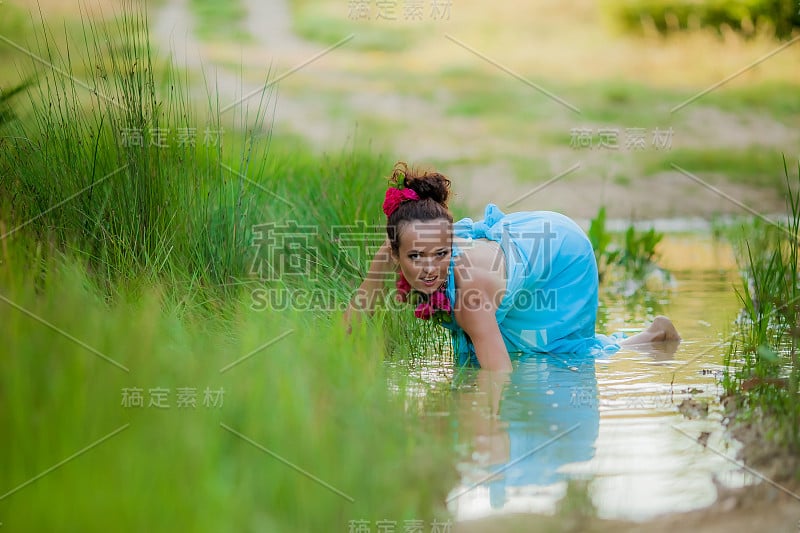 年轻的女模特躺在树林中的一个湖的背景上