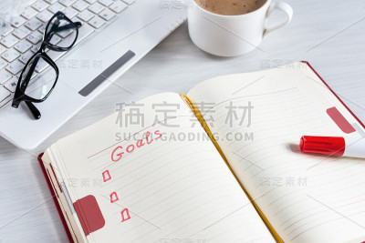 把目标列在笔记本上，电脑上，白色木桌上的咖啡杯上。