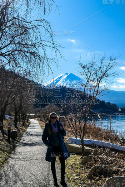 日本——一个女人走在川口町湖边，欣赏着富士山的景色