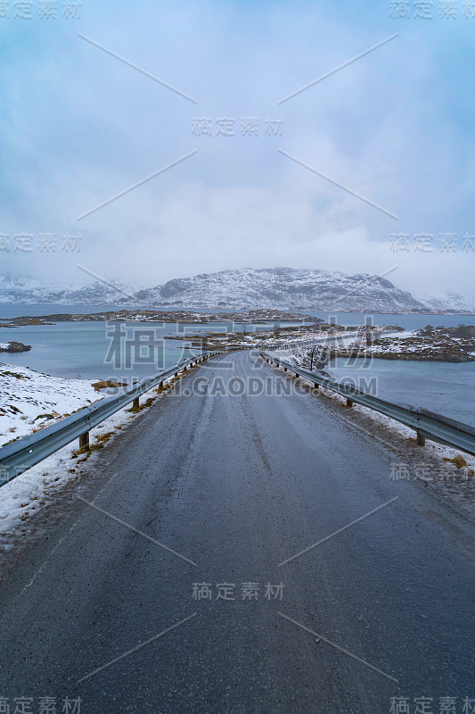 欧洲挪威诺德兰郡罗弗敦群岛的弗雷德旺大桥和公路。白雪皑皑的山峦和树木，是冬季自然景观的背景。著名的旅