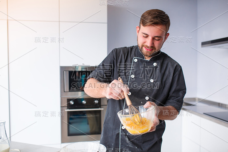 一个男人在厨房里做饭，在一个深盘子里打鸡蛋。烹饪的概念。