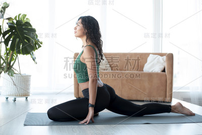 迷人的拉丁女人在客厅里做瑜伽。鸽子造成
