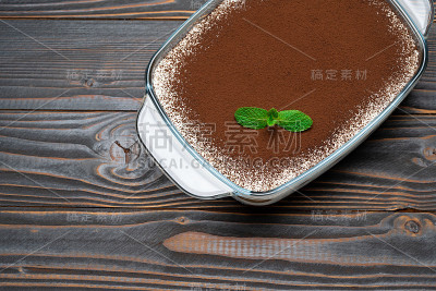 传统的意大利提拉米苏甜点在玻璃烤盘木制背景