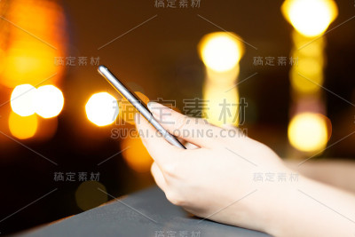 美丽的亚洲女孩在晚上使用手机