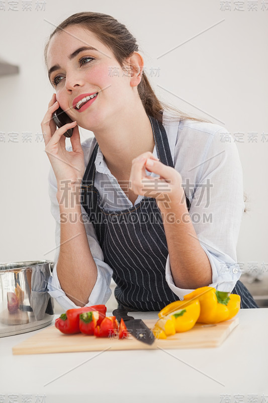 漂亮的褐发美女一边做饭一边打电话