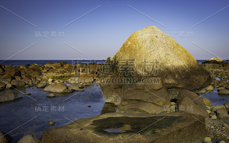 海景与大卵石和海水坑的岩石海滩在退潮