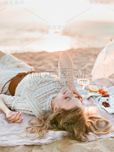 穿着蕾丝裙躺在沙滩上的女人。