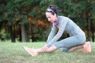 运动女性在户外伸展她的腿来热身