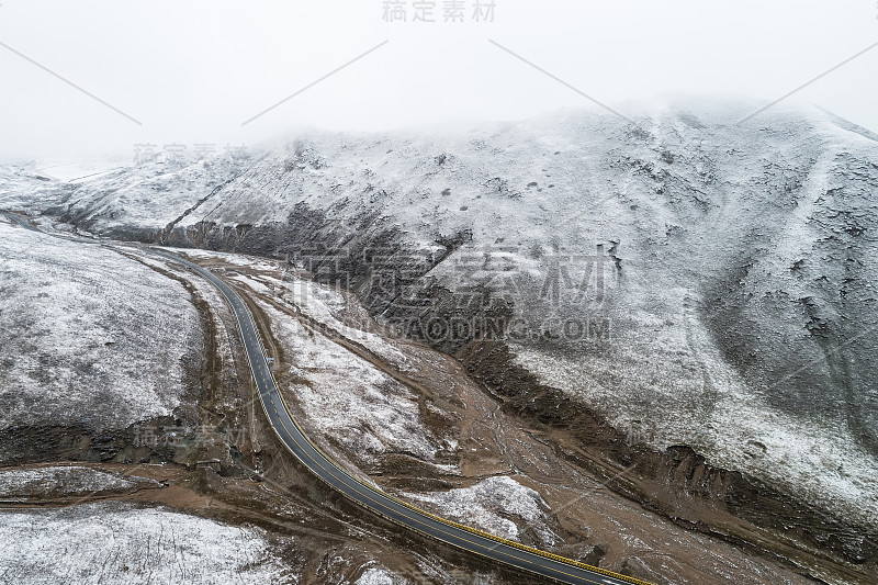 蜿蜒穿过被雪山环绕的山谷的乡村道路