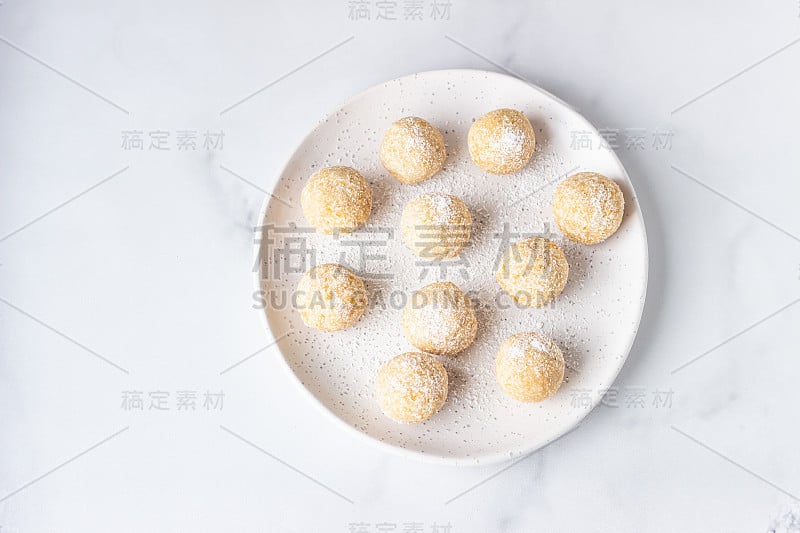 传统的印度节日糖果(Laddoo或Laddu)与椰子片上的陶瓷盘子，轻的背景，选择性的焦点。印度流行